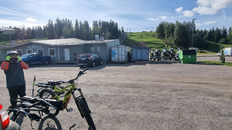 Poika pukee suojavarusteita päälle bikeparkin parkkipaikalla.