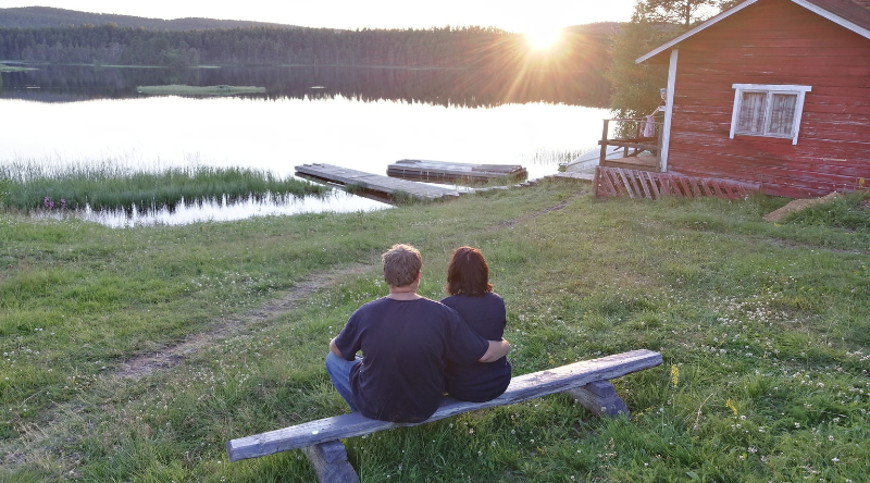 Pariskunta istuu penkillä ja katselee Lemmenjoelle